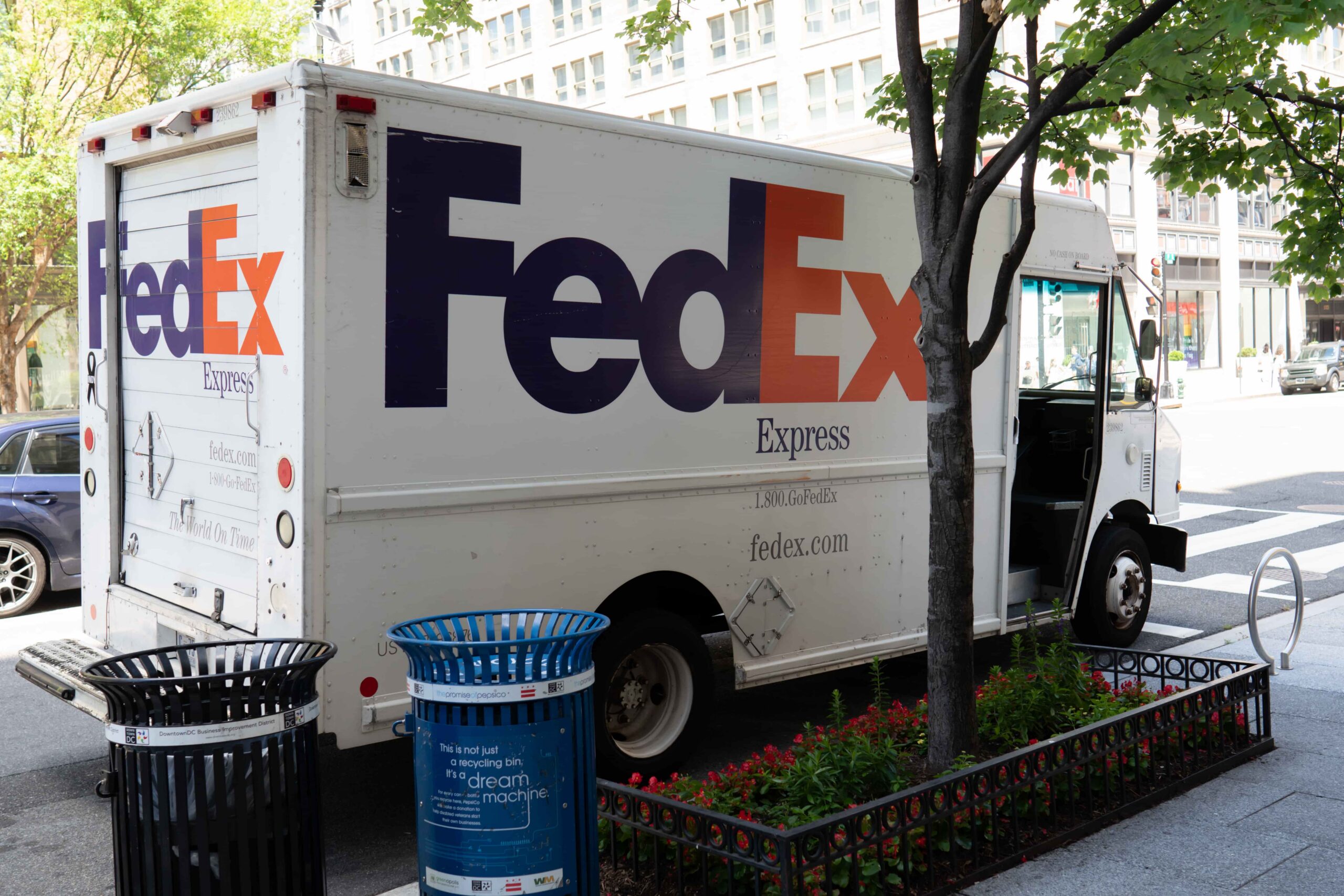 FedEx Express delivery truck parked on a city street near a sidewalk and buildings, representing package shipping and courier delivery services.