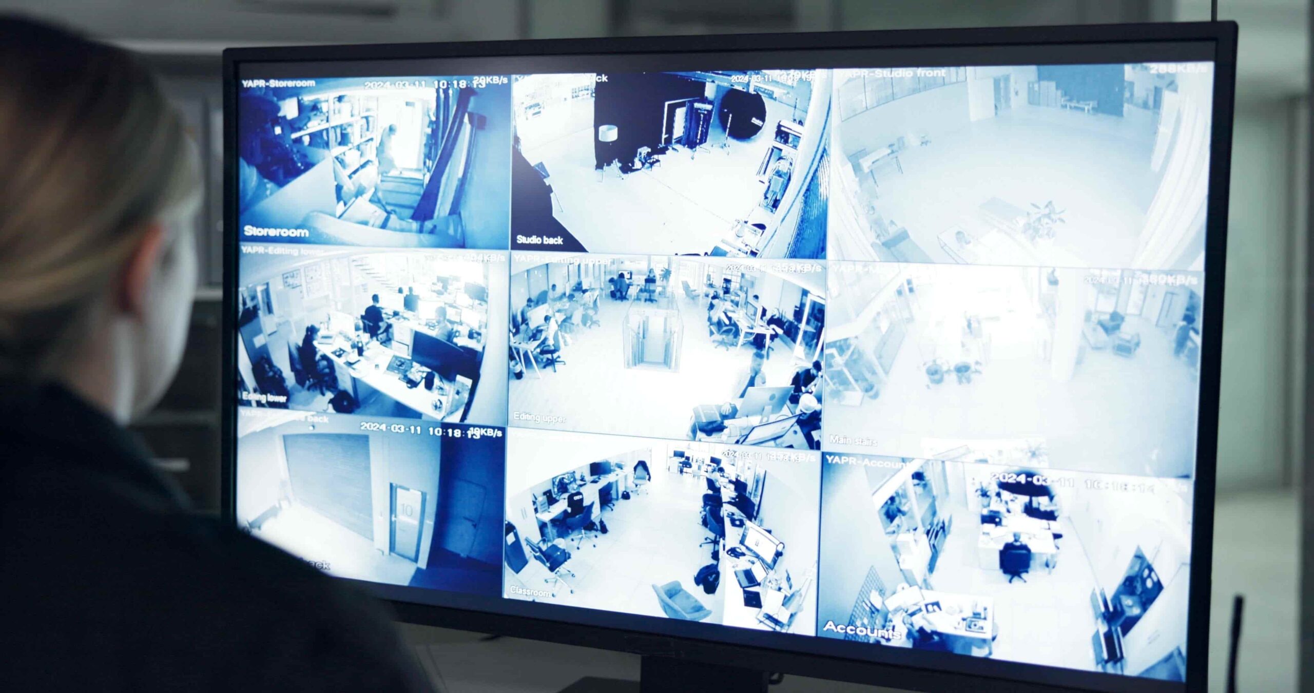 Security monitoring multiple CCTV camera feeds showing office and workplace surveillance footage