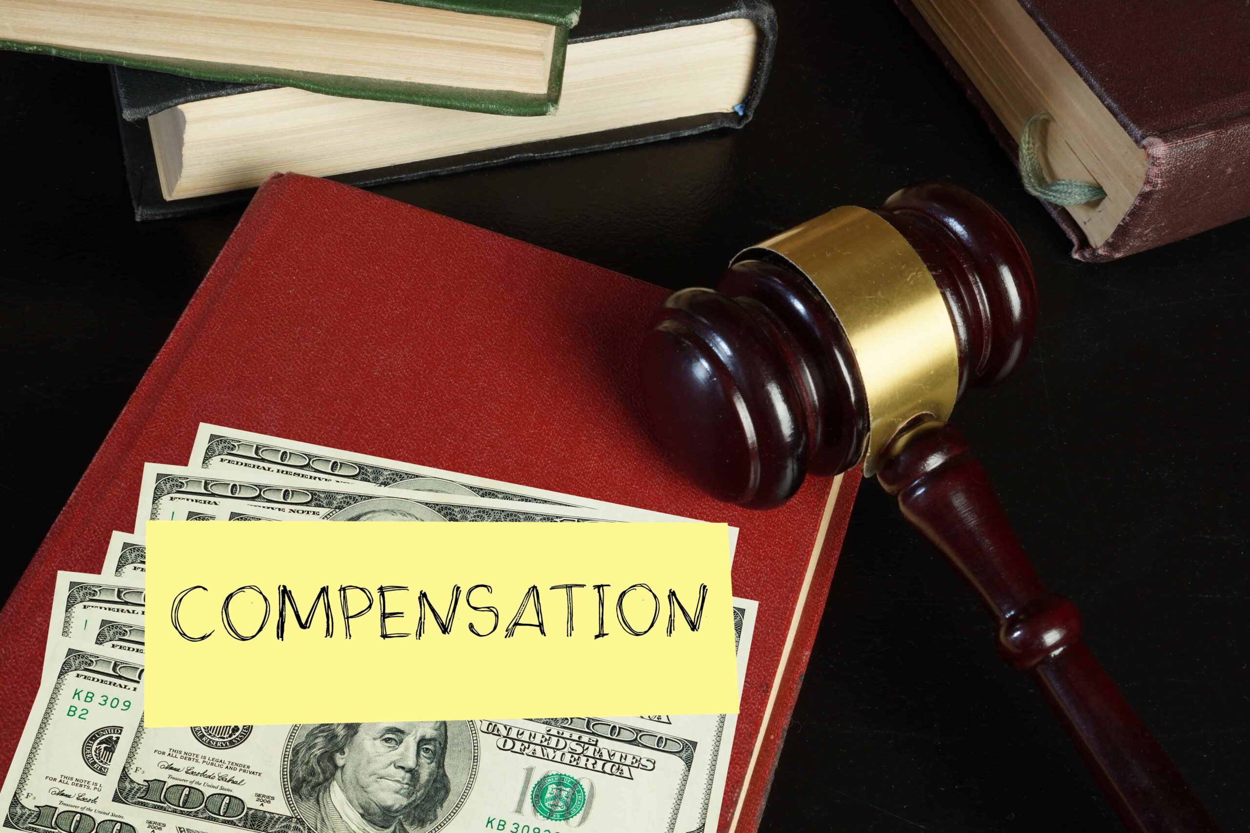 Legal compensation concept with gavel, law books, and U.S. dollar bills representing financial settlement or lawsuit compensation.